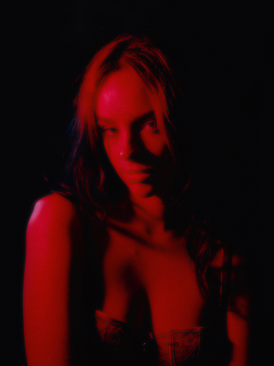 Mathilde Anne looking at the camera with a soft red light glowing over her face.